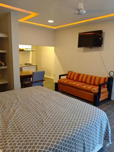 a bedroom with a bed and a couch and a tv at Loft Dee Dee centrical location in Puerto Vallarta