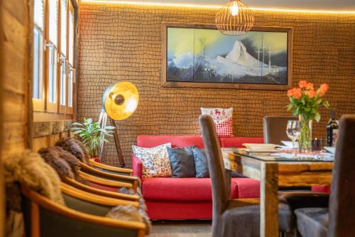 a living room with a red couch and a table at Schnapskeller in Zermatt