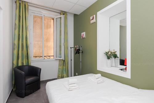 Cette chambre comprend un lit, une chaise et un miroir. dans l'établissement Residence Aout 32, à Cannes