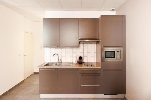 une cuisine avec des appareils électroménagers en acier inoxydable et des armoires brunes dans l'établissement Residence Aout 22, à Cannes
