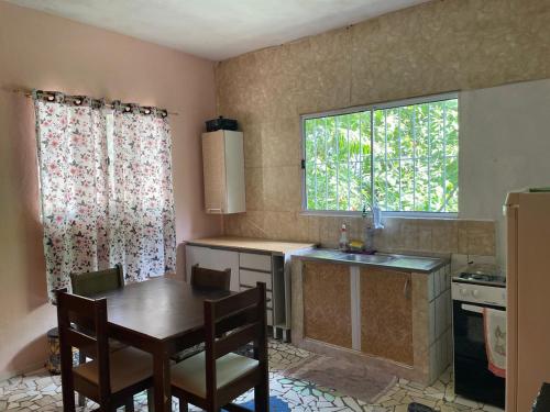 eine Küche mit Tisch und Spüle und Fenster in der Unterkunft Cantinho da serra do Guaraú in Peruíbe