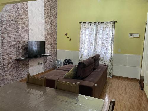 ein Wohnzimmer mit Couch und Flachbildfernseher in der Unterkunft Cantinho da serra do Guaraú in Peruíbe