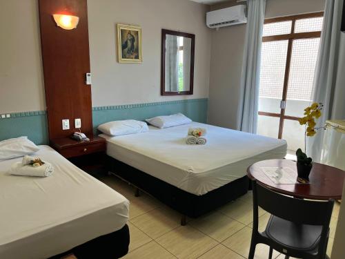 a hotel room with two beds and a table and a window at Hotel Alvorada Taguatinga by Bsb Inn in Taguatinga
