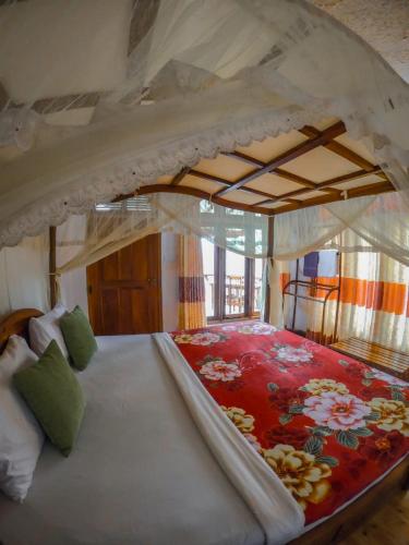 a bedroom with a large bed with a flower pattern at Mountain Range Cottage in Ella