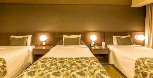 two beds in a hotel room with two lamps at Tauá Hotel & Convention Atibaia in Atibaia