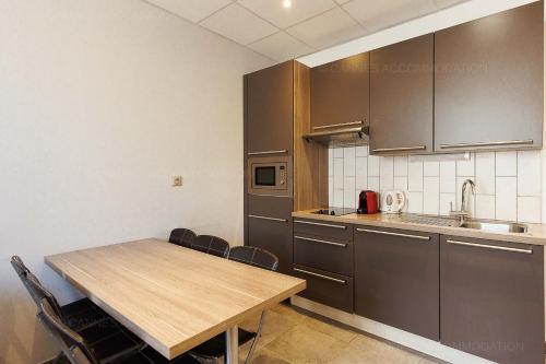 une cuisine avec une table en bois et quelques chaises dans l'établissement Residence Aout 31, à Cannes