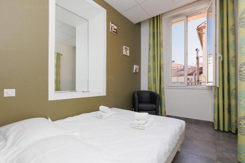 Cette chambre comprend un lit, une chaise et une fenêtre. dans l'établissement Residence Aout 21, à Cannes