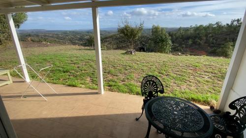 a porch with two chairs and a view of a field at Vale das Estrelas in São Teotónio