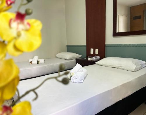 two beds in a room with yellow flowers at Hotel Alvorada Taguatinga by Bsb Inn in Taguatinga
