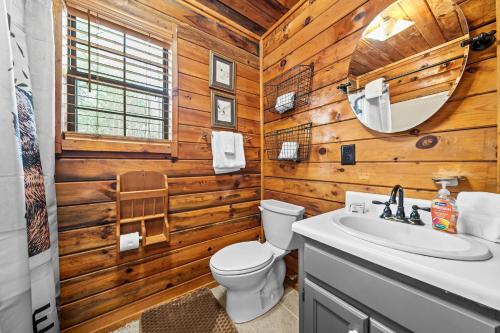 a bathroom with wooden walls and a toilet and a sink at Bear Hug Lodge in Ellijay