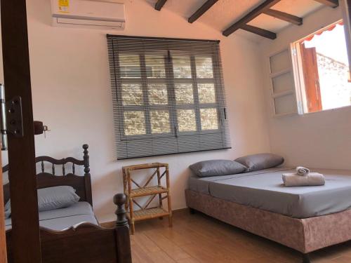 a bedroom with a bed and a chair and a window at Casa de Huéspedes El prado in Santa Marta