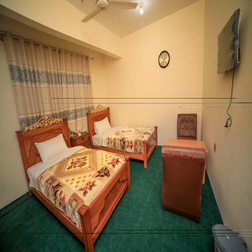 a room with two beds and a chair in it at Blue Sky Hotel & Restaurant in Skardu