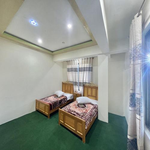two beds in a room with green carpet at Blue Sky Hotel & Restaurant in Skardu