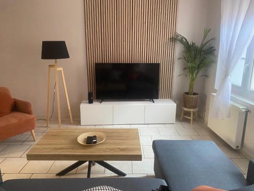 un salon avec une télévision et une table basse dans l'établissement L'escapade Douaisienne, à Douai