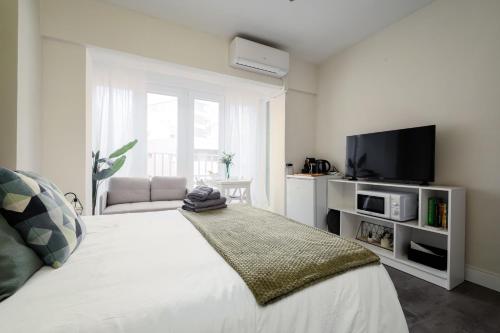 sypialnia z białym łóżkiem z telewizorem w obiekcie Beach Studio Apartment Playa Malagueta w Maladze