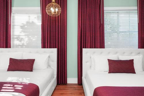 two beds in a room with red curtains at Catalina Hotel & Beach Club in Miami Beach