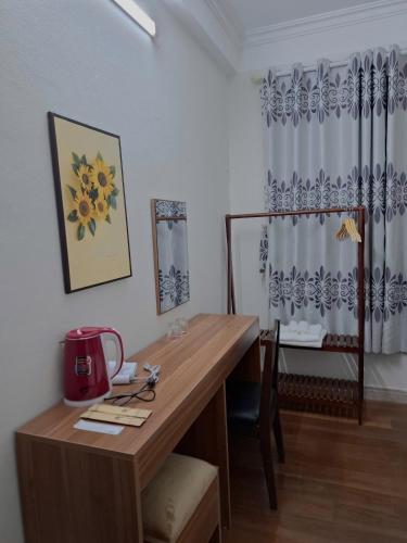 a room with a wooden desk with a table and a curtain at Airy Nest Hotel in Sóc Sơn