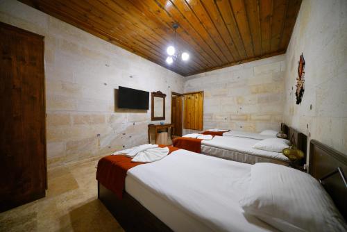 a room with two beds and a flat screen tv at Glory Art Stone House in Goreme