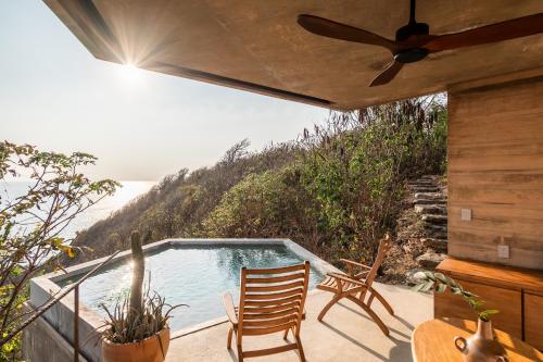 a patio with two chairs and a swimming pool at La Valise Mazunte, Member of Small Luxury Hotels in Zapotal