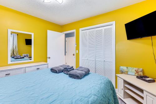 a bedroom with yellow walls and a bed with two pillows at Kure Beach Condo with Panoramic Ocean Views! in Kure Beach
