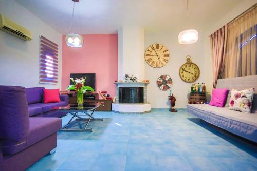 a living room with two purple couches and a clock at Villa Amor in Pefki Rhodes