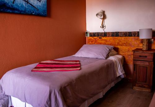 a bedroom with a bed with a blanket on it at Hotel Casa Algarrobo in San Pedro de Atacama