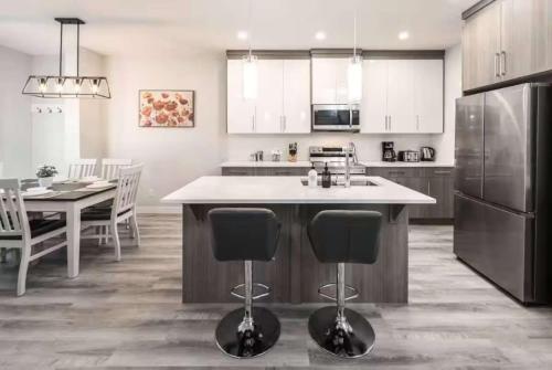 a kitchen with a kitchen island with chairs and a table at Stay Together! 2 Family Units, Sleeps 16! FREE Banff Pass, Parking, Wine, BBQ, & Netflix! in Calgary