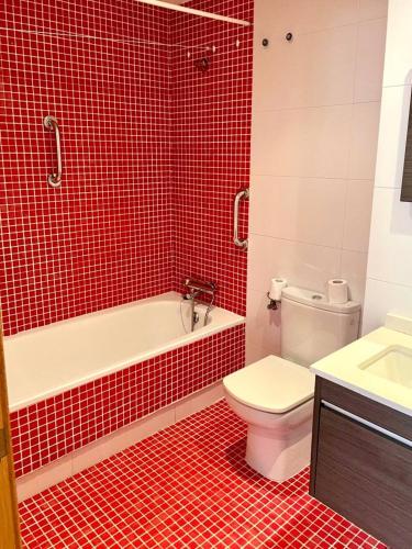 a red tiled bathroom with a toilet and a sink at Arnela in Baiona