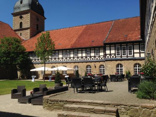 a building with a table and chairs and a clock tower at Klosterhotel Wöltingerode in Goslar