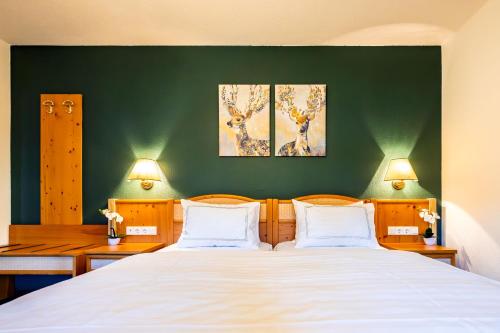 a bedroom with a large bed with two paintings on the wall at Landidyll Hinterhermsdorf by STEIGER Hotels in Hinterhermsdorf