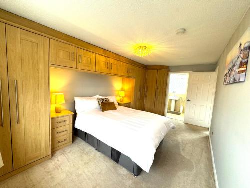 a bedroom with a large white bed and wooden cabinets at Cosy Guest House, Langley, Slough in Langley Station