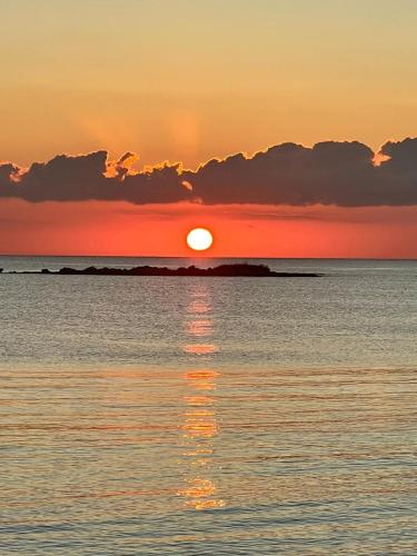 a sunset over the ocean with the sun reflecting in the water at Villa Eos con Piscina Privata nel cuore del Parco Naturale di Andrano in Andrano