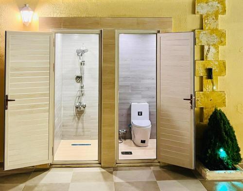a bathroom with two glass doors and a toilet at Kareem celebrations Hall صاله افراح in Irbid