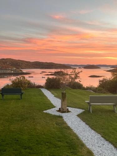 a gravel path with two benches and a view of the water at Eddrachilles Hotel in Scourie