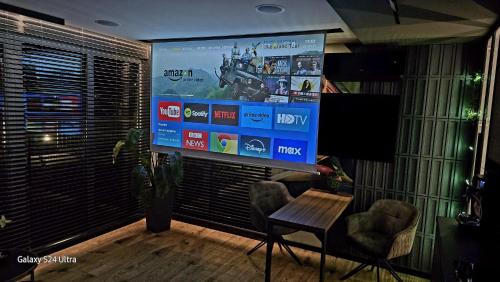 a large screen in a room with a table and chairs at Apartament Dark Prestige NEW ! - dostęp 24h, PROJEKTOR , garaż podziemny , klimatyzacja , duży taras in Kielce