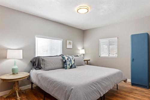 a bedroom with a bed and a table and two windows at #StayInMyDistrict Historic Charming Bungalow in Twin Falls