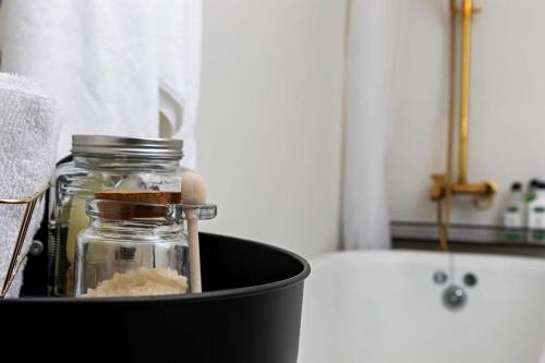 a glass jar sitting in a black container next to a bath tub at #StayInMyDistrict Historic Charming Bungalow in Twin Falls