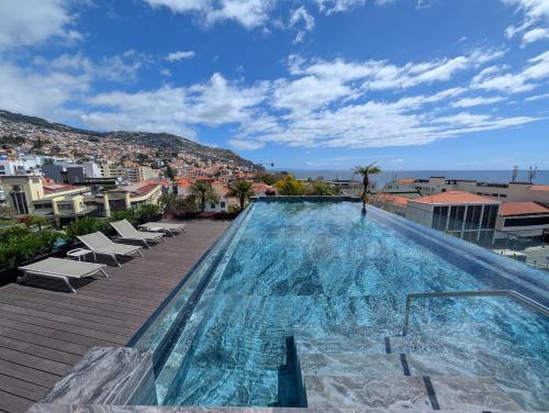 a large swimming pool with chairs and a city at Savoy Residence City Loft - Style and Sophistication in Funchal