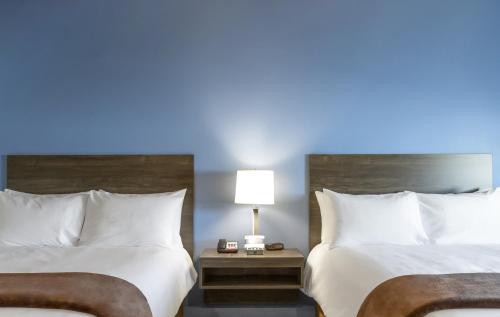 two beds in a hotel room with a blue light at My Place Hotel-Huntersville, NC in Huntersville