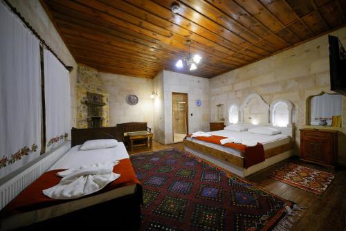 a bedroom with two beds and a wooden ceiling at Glory Art Stone House in Goreme
