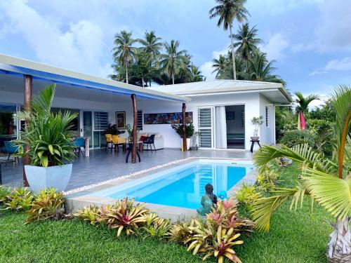 a villa with a swimming pool in front of a house at Tahiti - Bay Lodge in Taravao
