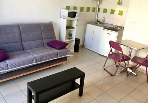 un salon avec un canapé et une table et une cuisine dans l'établissement Résidence Noisica, à Saint-Étienne