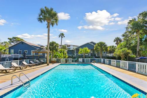 a swimming pool with a deck and palm trees at Folliday Inn - The Overnighter - Room 25 in Folly Beach