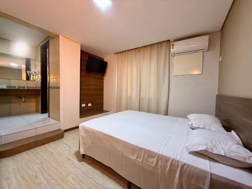 a bedroom with a large white bed and a television at Granville Hotel in Curitiba