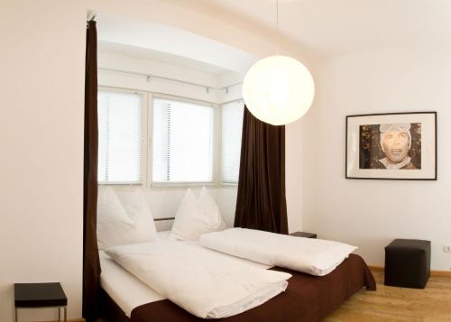 a bedroom with a bed with white sheets and a window at Arnsteiner Apartments in Zell am See