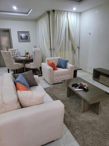 Una sala de estar con dos sofás blancos y una mesa. en Outstand-Chouette Luxury Apartment, en Abuja