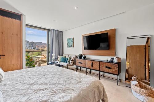 a bedroom with a large bed with a flat screen tv at Zantamar - Beachfront Suites in La Cruz in Cruz de Huanacaxtle