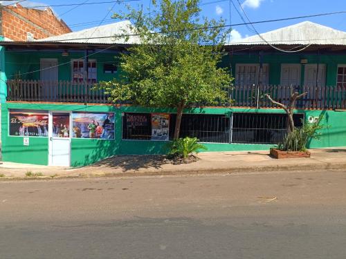 a green building on the side of a street at Hostel el Amanecer in Puerto Iguazú