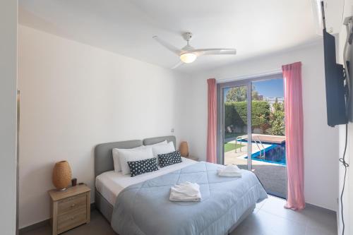 a bedroom with a bed and a window with a pool at Sea Satin Villas - Ayia Napa Center in Ayia Napa