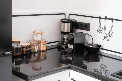 a counter with a coffee maker and jars on it at Grammy's room 1 in Karpenision